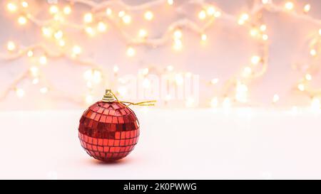 Brillante disco rosso ornamento palla di Natale su sfondo bianco con decorativelights Foto Stock