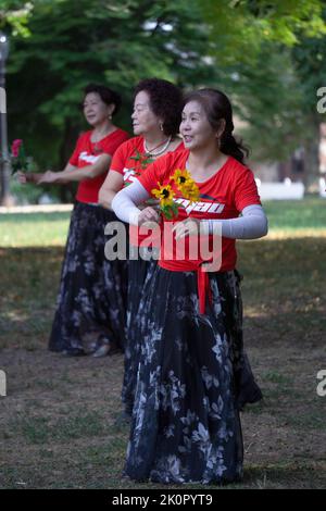 Fa parte di un grande gruppo di donne cinesi americane in una lezione di danza e di esercizio yuanji in un parco a Queens, New York. È una tradizione cinese del mattino. Foto Stock