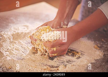 L'arte di preparare la pasta. Una persona che impasta la pasta su un tavolo infarinato. Foto Stock