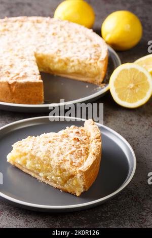 Deliziosa torta grattugiata con primo piano di cagliata al limone in un piatto sul tavolo. Verticale Foto Stock
