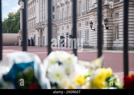 LONDRA, Regno Unito - Settembre 2022: Guardie a Buckingham Palace viste attraverso tributi floreali alla Regina Elisabetta II Foto Stock