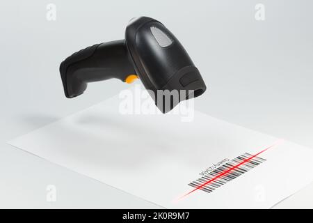 Lo scanner per codici a barre nero esegue la scansione di un codice a barre su una pagina bianca.elaborazione automatica delle informazioni Foto Stock