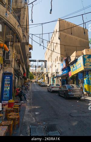 06.18.2022. Amman, Giordania. Una strada stretta locale ad Amman con piccoli mercati, persone e automobili. Foto di alta qualità Foto Stock