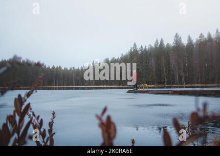 L'esploratore si trova alla fine di un molo, respirando aria fresca, sotto la pioggia del lago di pieni-Vimpeli vicino alla città di Kajaani, nella regione di Kainu, Finlandia. L'ultimo Foto Stock