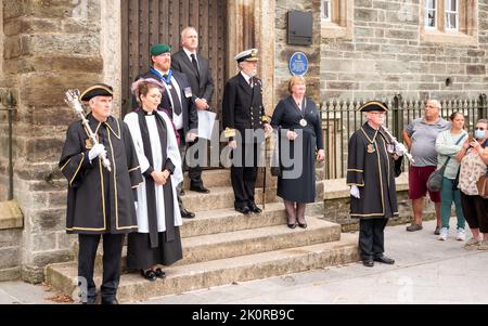 Il Clerk del comune di Tavistock, Carl Hearn, ha letto la proclamazione dei passi della Guildhall, insieme a dignitari e dirigenti civici, tra cui Ric Cheadle (Vice Presidente del Devon), il Consigliere James Ellis (Vice Sindaco di Tavistock), il Consigliere Caroline Mott (Sindaco del Devon occidentale), il Consigliere della contea Debo Sellis, Reverendo Rosie Illingworth, accompagnato dai portacolori del Mace della Città Foto Stock