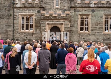 Il Clerk del comune di Tavistock, Carl Hearn, ha letto la proclamazione dei passi della Guildhall, insieme a dignitari e dirigenti civici, tra cui Ric Cheadle (Vice Presidente del Devon), il Consigliere James Ellis (Vice Sindaco di Tavistock), il Consigliere Caroline Mott (Sindaco del Devon occidentale), il Consigliere della contea Debo Sellis, Reverendo Rosie Illingworth, accompagnato dai portacolori del Mace della Città Foto Stock