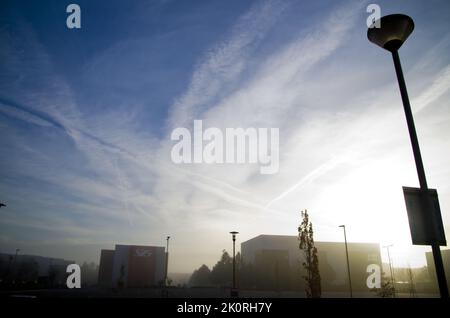 Cielo blu spettacolare all'alba con nuvole di whisky e jet trail sul paesaggio industriale. Foto Stock