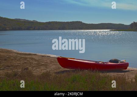 Il kayak rosso si tirò sulla riva del fiume. Foto Stock