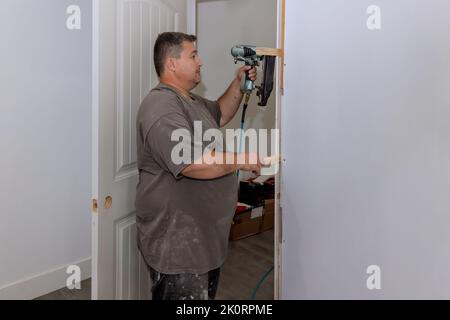 L'operatore addetto ai rivestimenti installa le portiere interne in una nuova casa Foto Stock