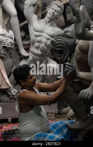 Un uomo che dipinge Durga idol con l'uso di fuoco selettivo su una parte particolare dell'uomo con il resto dell'uomo, l'idolo e tutto il resto sfocato. Kolk Foto Stock