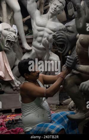 Un uomo che dipinge Durga idol con l'uso di fuoco selettivo su una parte particolare dell'uomo con il resto dell'uomo, l'idolo e tutto il resto sfocato. Kolk Foto Stock