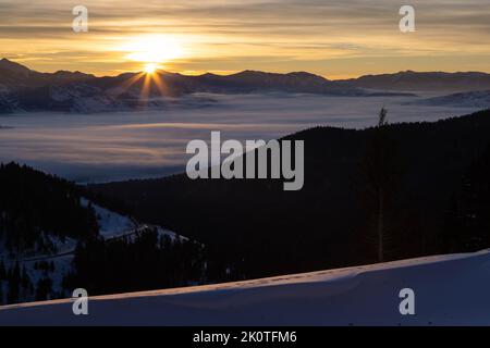 Il sole che sorge sopra i Monti Gros ventre e l'estremità meridionale di Jackson Hole ricoperta di nebbia. Bridger-Teton National Forest, Wyoming Foto Stock