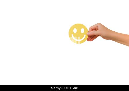 Mano femminile che tiene giallo sorriso felice faccia carta taglio, buon feedback rating, recensione positiva del cliente, esperienza, sondaggio sulla soddisfazione, salute mentale Foto Stock