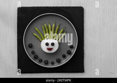 volti divertenti da blackberry e raddish, modo creativo sul piatto isolato Foto Stock