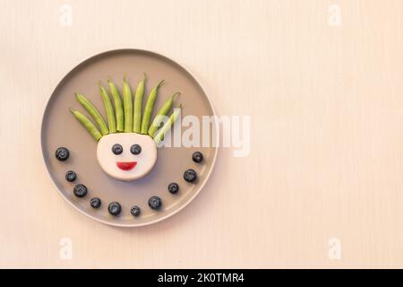 volti divertenti da blackberry, fagioli e raddish, modo creativo sul piatto isolato Foto Stock