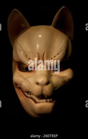 Uno scatto verticale di una maschera giapponese kitsune usata nel teatro Noh isolato su uno sfondo nero Foto Stock