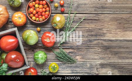 Varietà di pomodori non trattati multicolore su un vecchio tavolo di legno, vista dall'alto con spazio copia Foto Stock