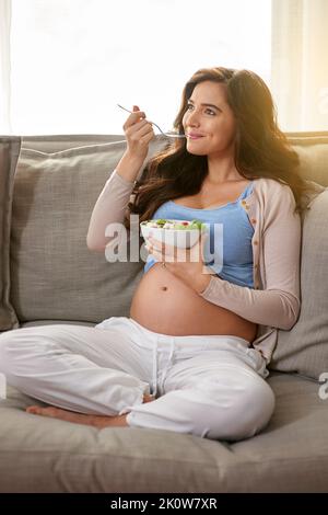 mamma sana, bambino sano. Una donna incinta che mangia un'insalata sana a casa. Foto Stock