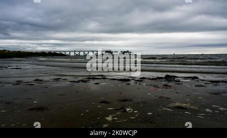 NORWALK, CT, USA - 13 SETTEMBRE 2022 : dopo la tempesta nuvole sulla spiaggia con molo di pesca in lontananza Foto Stock