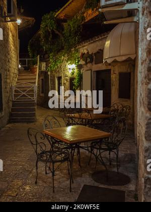 Strada vuota caffè terrazza con tavoli e sedie nel centro storico di Budva di notte Foto Stock