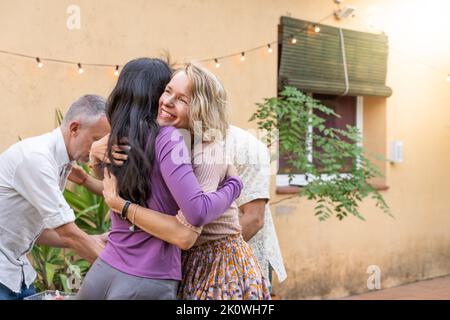 Gli amici multietnici di mezza età si salutano e si accoccolano insieme felicemente. Foto Stock