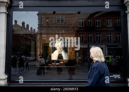 Londra, Regno Unito. 13th Set, 2022. Una donna si ferma e guarda il ritratto della Regina Elisabetta II visualizzato sulla vetrina di Selfridges. I negozi sono un tributo alla Regina Elisabetta II sulla strada principale nel centro di Londra. (Foto di Hesther ng/SOPA Images/Sipa USA) Credit: Sipa USA/Alamy Live News Foto Stock