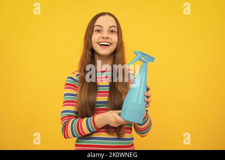 Giovane ragazza che tiene il flacone di detergente. Happy Kid tenere disinfettante spray prodotto in bottiglia per spazio copia sfondo giallo, disinfezione. Foto Stock