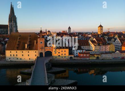 Regensburg, Germania. Un drone del vecchio ponte di pietra, Bruckturm, Dom St Peter, e altri edifici nel centro storico della città all'alba Foto Stock