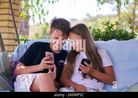 ragazzi ragazza seduta sul terrazzo con i dispositivi Foto Stock