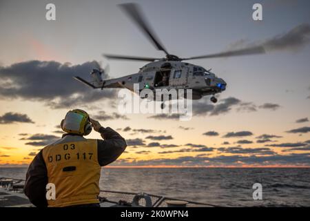 220903-N-GF955-1074 MAR BALTICO (SETT. 3, 2022) U.S. Navy Boatswain’s Mate 1st Class Nicholas Labarre, di Chicago, Illinois, saluta un elicottero fregato della Royal Netherlands Navy NH-90 NATO (N-195) dal ponte di volo del cacciatorpediniere missilistico guidato di classe Arleigh Burke USS Paul Ignatius (DDG 117), 3 settembre 2022. Paul Ignatius fa parte del Kearsarge Amphibious Ready Group e ha imbarcato 22nd Marine Expeditionary Unit, sotto il comando e il controllo della Task Force 61/2, in un'implementazione programmata nell'area operativa delle forze Navali USA in Europa, impiegata dalla U.S. Sesta flotta per difendere gli Stati Uniti, allie Foto Stock