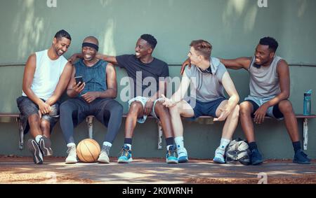 Basket, sport e amici con una squadra di uomini seduti su una panchina dopo l'allenamento, la pratica o una partita. Lavoro di squadra, telefono ed esercizio con un gruppo di Foto Stock