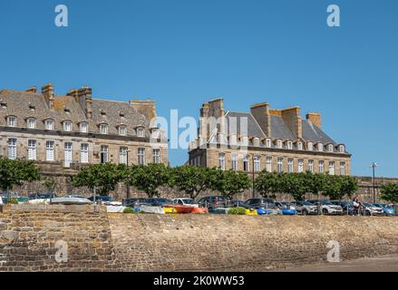 St. Malo, Bretagna, Francia - 8 luglio 2022: Manioni e palazzi lungo Rue D'Orleans raggiungendo Bastion Saint Louis sotto il cielo blu. Fare il paaking con le auto aggiungere c Foto Stock