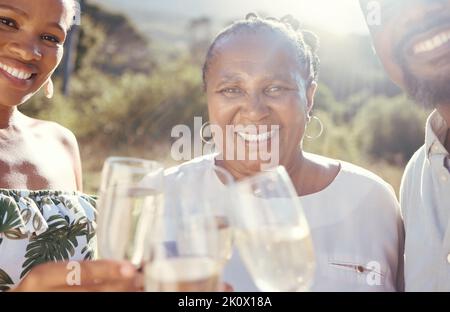 Famiglia nera con un bicchiere di vino in natura che dà un brindisi per festeggiare in campagna. Ritratto di felice popolo africano bevendo champagne di lusso Foto Stock