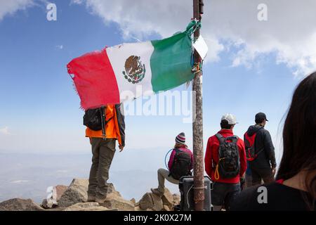 Bandiera messicana sulla cima di una montagna, arrampicatori in messico, nevado de colima vulcano. Foto Stock