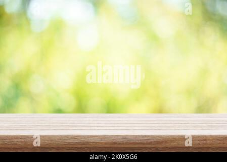 Tavolo di legno vuoto e sfondo verde bokeh natura. Mockup per esterni per montaggio su display di prodotti alimentari. Giardino estivo con sfondo sfocato e scrivania rustica pla Foto Stock