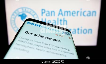 Telefono cellulare con sito web della Pan American Health Organization (PAHO) sullo schermo di fronte al logo. Messa a fuoco in alto a sinistra del display del telefono. Foto Stock