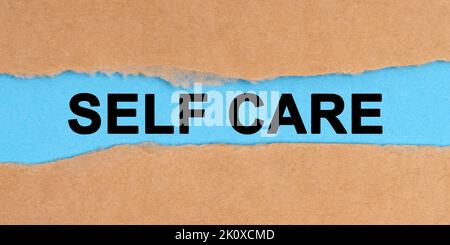 Concetto di medicina. La carta è strappata al centro. All'interno su uno sfondo blu è scritto - Self Care Foto Stock