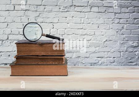 Libro d'epoca e lente d'ingrandimento. Concetto di educazione. Foto Stock