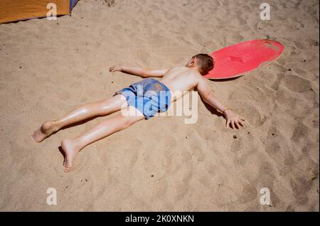 Boy prendere il sole a Hope Cove, Kingsbridge, Devon, Inghilterra, Regno Unito. Foto Stock