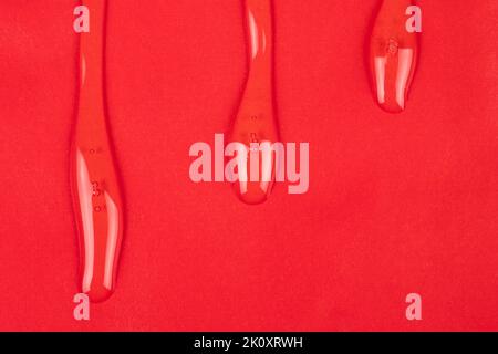 vernice trasparente, gocce d'olio trasparente su sfondo rosso dello spazio di copia. Foto Stock