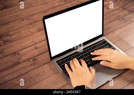 Il notebook moderno si fa mimare, le mani della donna che scrivono sul notebook moderno si fa mimare. Notebook su tavolo in legno. Le mani di una donna caucasica sullo schermo bianco o sul display Foto Stock