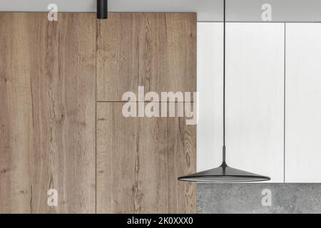 Cucina moderna e minimalista con interni in sala da pranzo con superfici in legno, grigio e bianco. Elegante lampada da soffitto nera da vicino. Estetica semplice inter Foto Stock