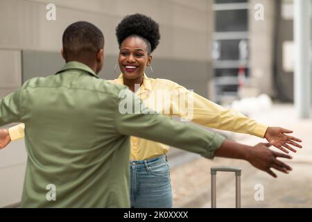 Felice marito africano incontro moglie dopo il viaggio abbracciando all'aeroporto Foto Stock