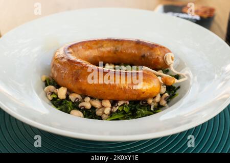 salsiccia tipica portoghese affumicata fritta con fagioli e verdure su piatto bianco Foto Stock