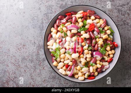 Insalata vegetariana di tre fagioli primo piano in una ciotola sul tavolo. Vista orizzontale dall'alto Foto Stock