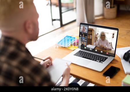 Albino afro-american uomo che effettua videochiamate con un computer portatile con diversi colleghi sullo schermo. Comunicazione aziendale, lavoro flessibile, inclusività e digi Foto Stock