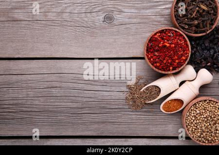 Le spezie si mescolano su cucchiai di legno su sfondo grigio. Foto Stock