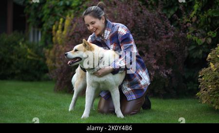 La ragazza gioca e abbraccia il suo amato cane Akita Inu. Foto Stock