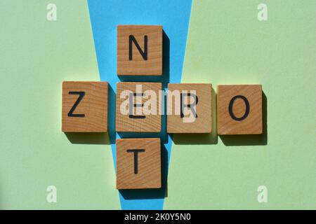 NET Zero, parole in lettere alfabetiche di legno a forma di croce su sfondo blu e verde Foto Stock