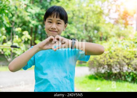 Ritratto di mani felici del bambino gesto a forma di cuore mostrando amore e gentilezza. Concetto di Amore, Giornata Mondiale del cuore. Foto Stock